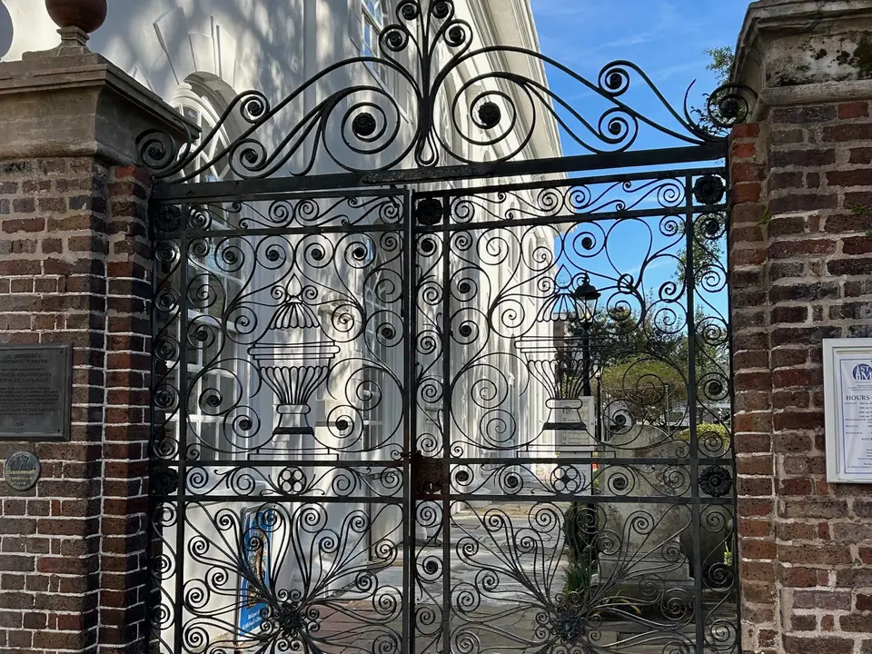 Example of ornate scrolled wrought iron gates between brick pillars